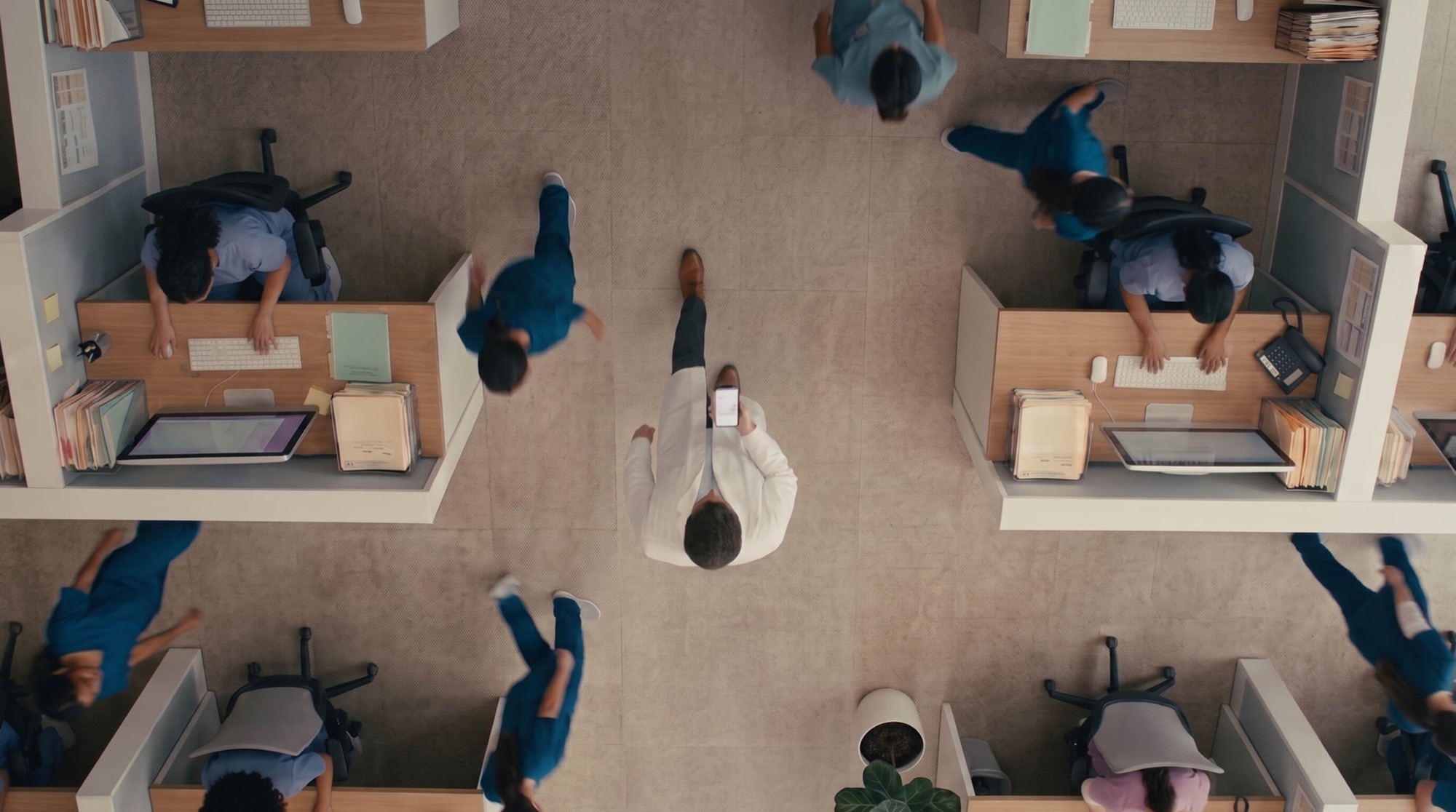 A physician crossing a busy clinic floor, phone in hand
